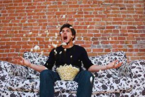 Uomo infuriato su divano lancia in aria i pop corn